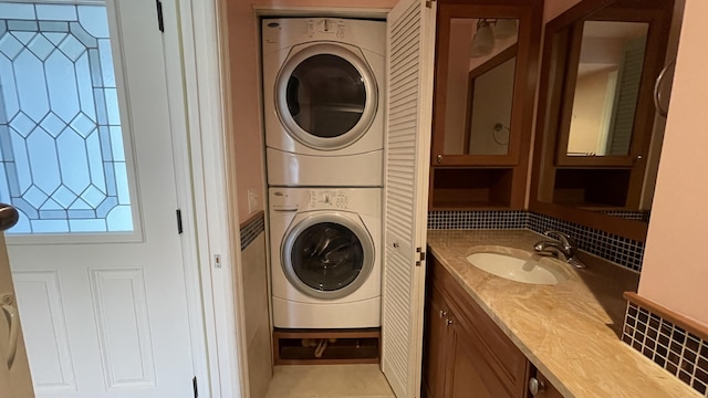 clothes washing area featuring stacked washing maching and dryer and a sink
