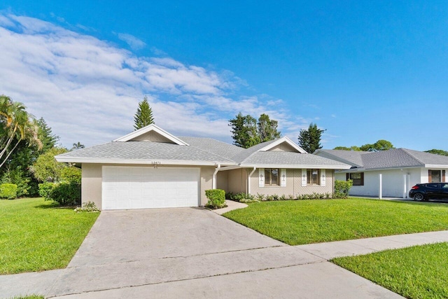ranch-style home with concrete driveway, stucco siding, a front yard, and a garage