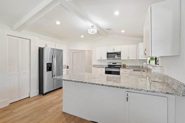 kitchen with light wood finished floors, stainless steel appliances, a peninsula, a sink, and light stone counters