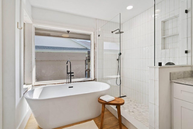 full bathroom featuring a soaking tub, wood finished floors, a walk in shower, and recessed lighting