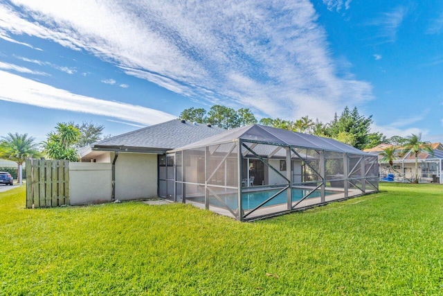 rear view of property featuring a yard, a shingled roof, and an outdoor pool