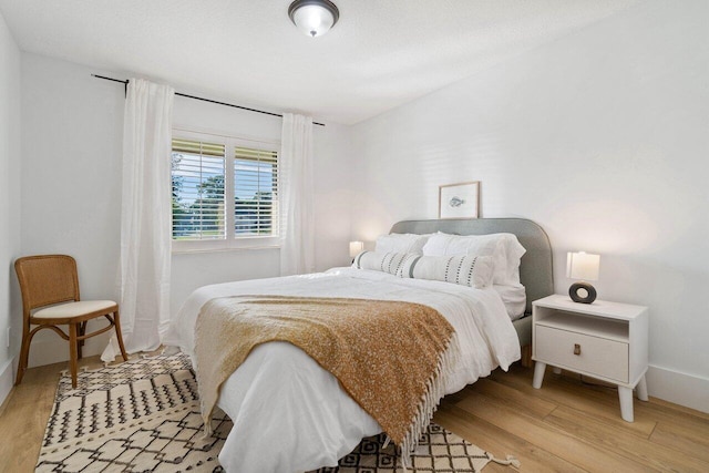bedroom featuring light wood finished floors and baseboards