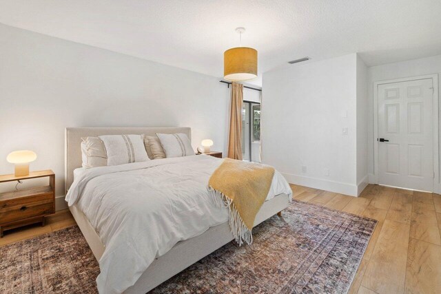 bedroom with baseboards, light wood finished floors, and visible vents