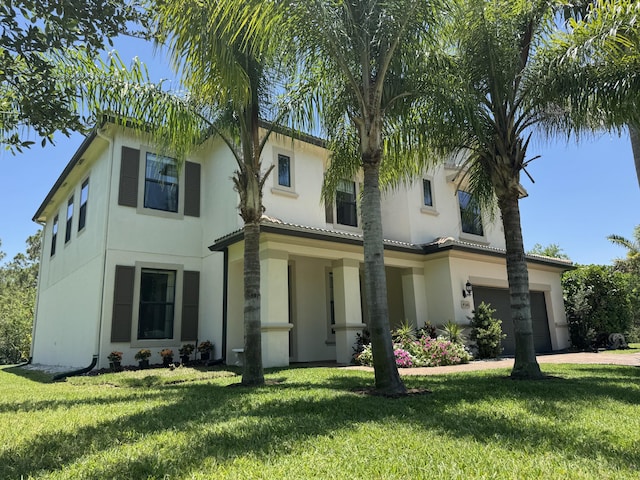 mediterranean / spanish-style home featuring stucco siding, a front yard, and driveway