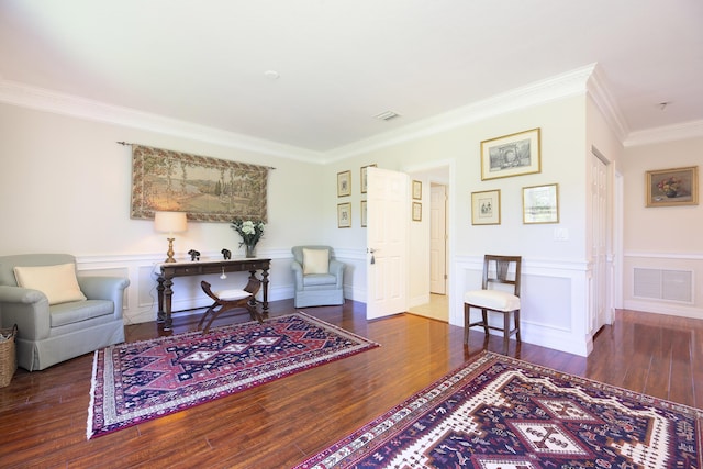 sitting room featuring ornamental molding, wood finished floors, and a wainscoted wall