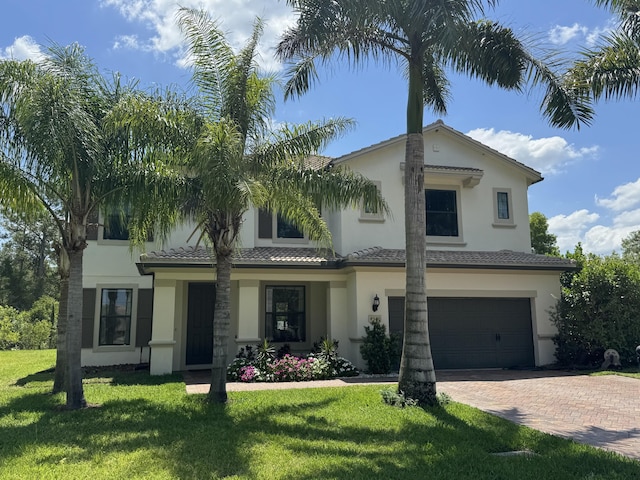 view of front of home with stucco siding, decorative driveway, an attached garage, and a front lawn