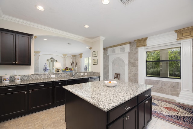 kitchen featuring light stone countertops, dishwasher, ornamental molding, a center island, and light tile patterned floors
