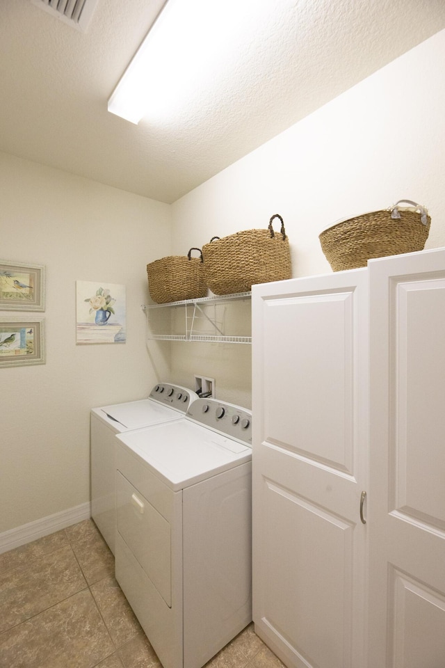 clothes washing area featuring washing machine and clothes dryer, baseboards, and light tile patterned floors