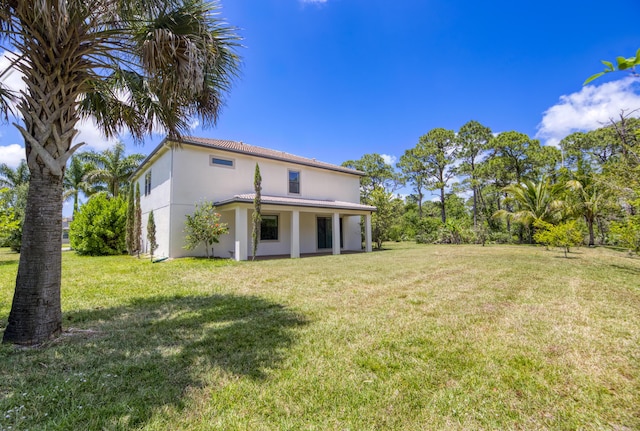 rear view of property featuring a lawn and stucco siding