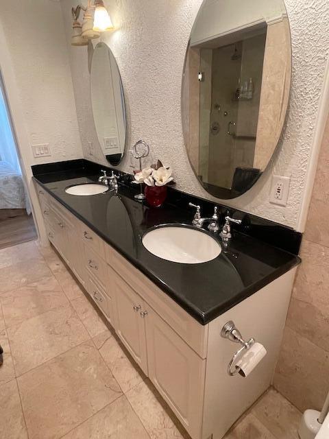 1028 SE 13th Ct, Deerfield Beach, FL 33441 - bathroom featuring a sink, a textured wall, and double vanity