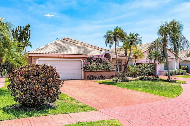 view of front of house featuring a tile roof, decorative driveway, a front lawn, an attached garage, and stucco siding