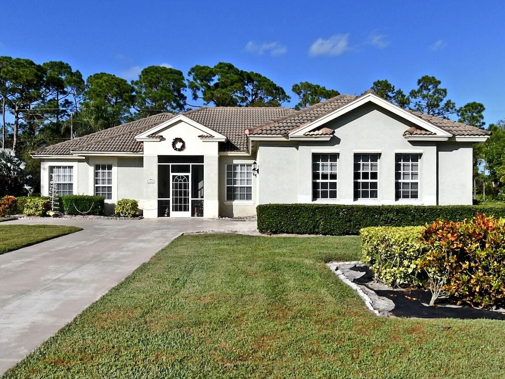 view of front of house featuring a tile roof, a front yard, and stucco siding