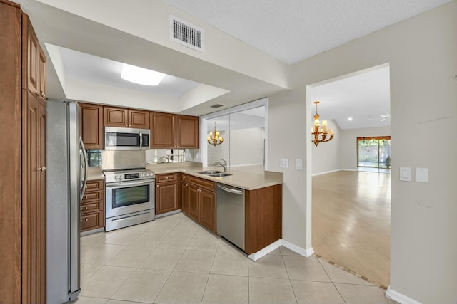 11206 Applegate Cir, Boynton Beach, FL 33437 - kitchen with an inviting chandelier, brown cabinetry, stainless steel appliances, light countertops, and visible vents