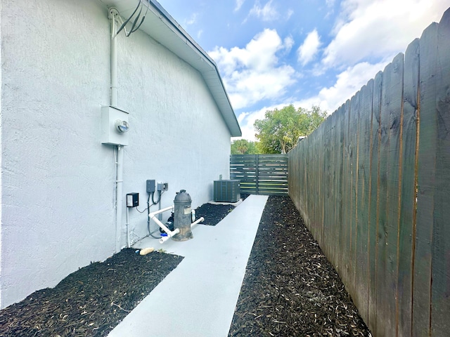 view of home's exterior with central AC, fence, and stucco siding
