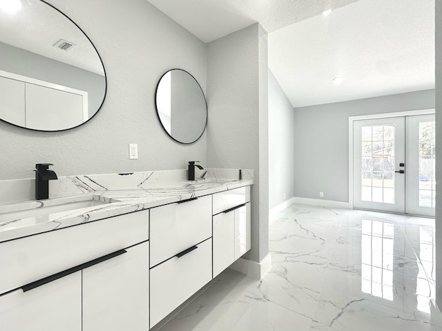 bathroom with a sink, marble finish floor, double vanity, baseboards, and visible vents
