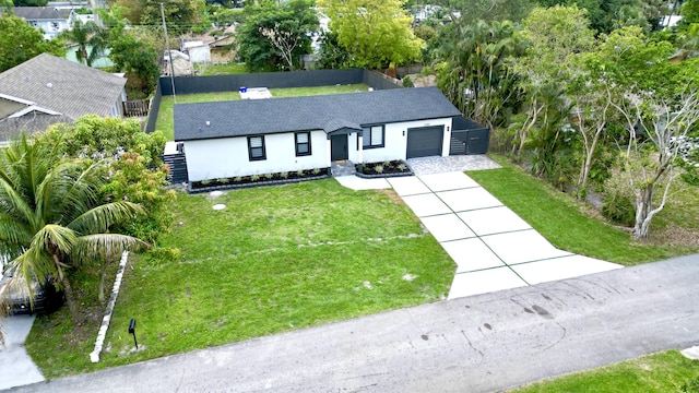 ranch-style house with stucco siding, an attached garage, concrete driveway, roof with shingles, and a front yard