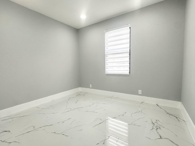 spare room with marble finish floor and baseboards