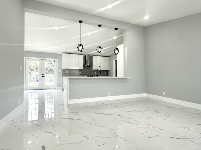 kitchen featuring white cabinets, french doors, baseboards, and wall chimney range hood