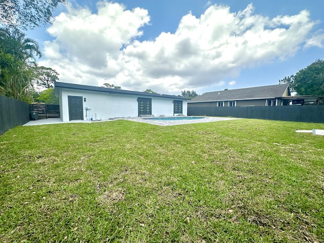 rear view of property featuring a fenced in pool, a fenced backyard, a patio area, a yard, and stucco siding