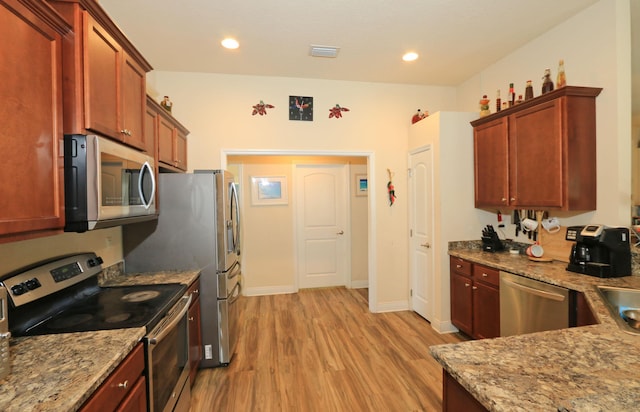 kitchen with light stone counters, light wood-style flooring, stainless steel appliances, recessed lighting, and visible vents