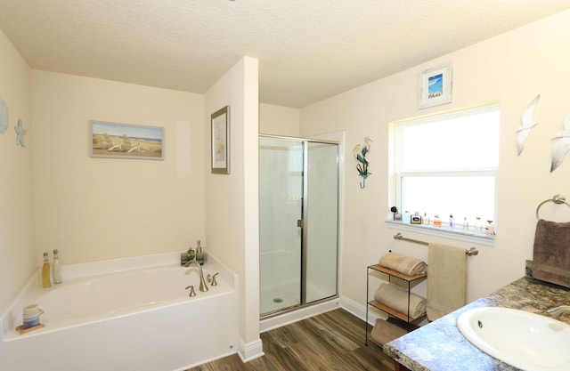 full bath featuring a garden tub, a stall shower, a textured ceiling, and wood finished floors