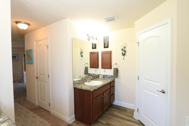 bathroom featuring vanity, baseboards, a textured ceiling, and visible vents