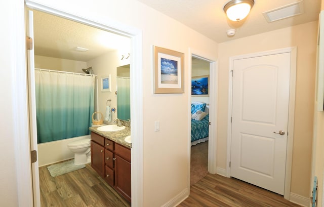 bathroom with double vanity, shower / bathtub combination with curtain, wood finished floors, and visible vents