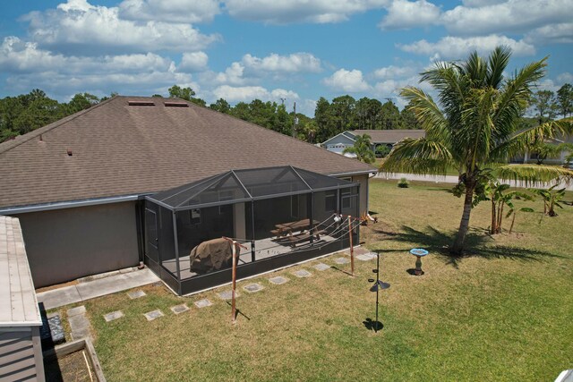 back of house featuring a lawn, a patio, a shingled roof, and a lanai