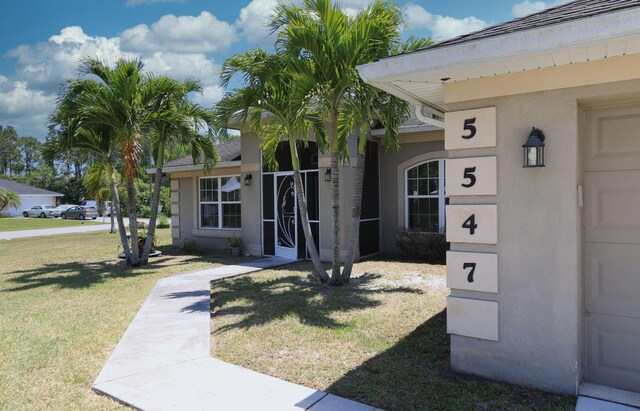 doorway to property with a lawn and stucco siding