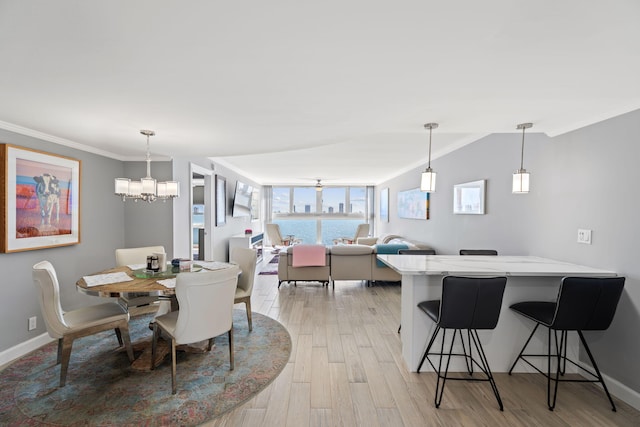 dining area with an inviting chandelier, ornamental molding, light wood finished floors, and baseboards