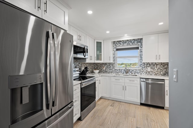 kitchen with tasteful backsplash, a sink, light countertops, white cabinets, and appliances with stainless steel finishes