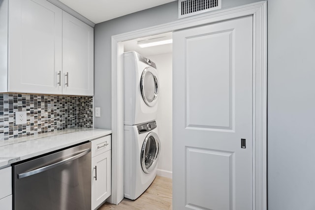 clothes washing area featuring visible vents, light wood finished floors, stacked washer / dryer, and laundry area