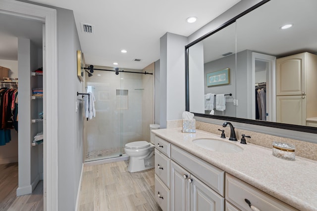full bath featuring wood finished floors, visible vents, toilet, vanity, and a stall shower