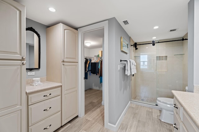 full bath with toilet, wood finished floors, vanity, and a stall shower