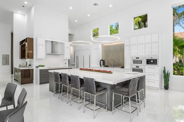 5784 Vintage Oaks Cir, Delray Beach, FL 33484 - kitchen featuring wall chimney range hood, a healthy amount of sunlight, modern cabinets, and a high ceiling