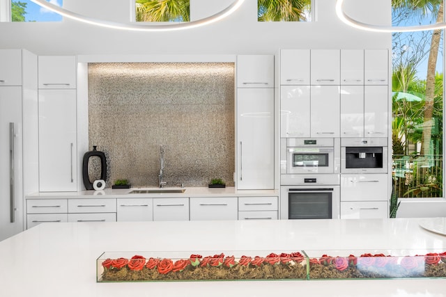 5784 Vintage Oaks Cir, Delray Beach, FL 33484 - kitchen with white double oven, light countertops, white cabinets, a sink, and modern cabinets