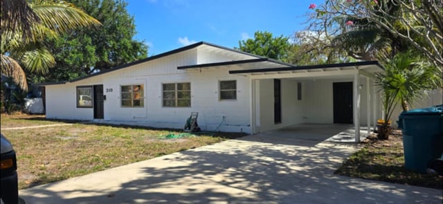 view of front facade featuring a front lawn, concrete driveway, and an attached carport