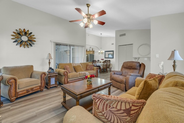 living area with high vaulted ceiling, ceiling fan with notable chandelier, light wood-type flooring, and visible vents