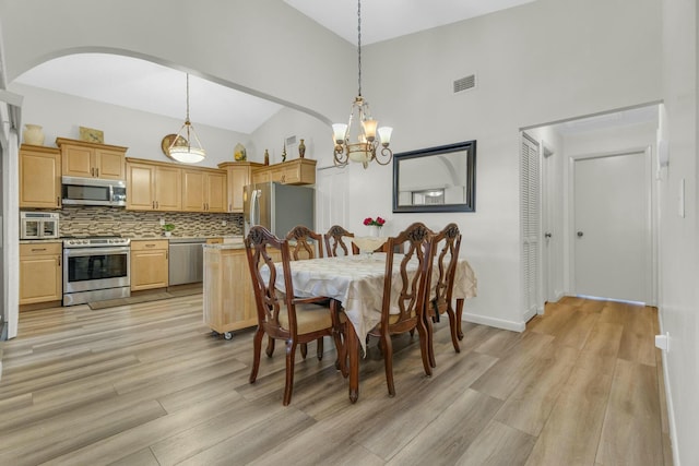 dining area featuring arched walkways, high vaulted ceiling, a chandelier, light wood-style flooring, and visible vents