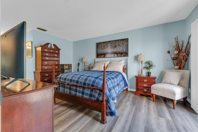 bedroom with connected bathroom, visible vents, and light wood-style floors