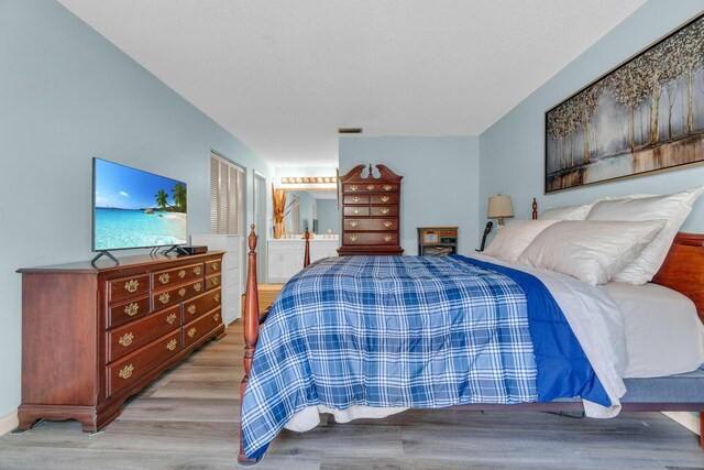 bedroom with a textured ceiling, access to exterior, and wood finished floors