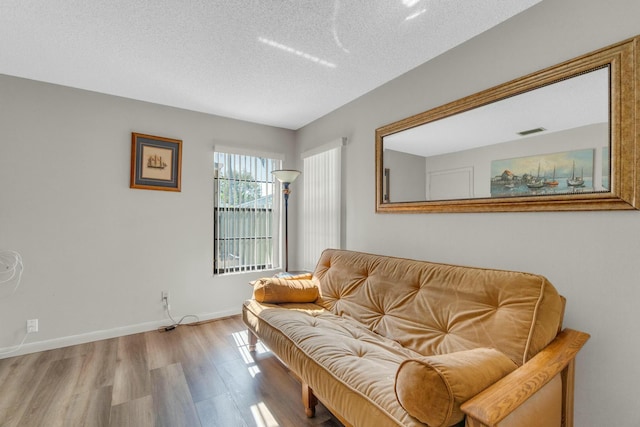 sitting room featuring a textured ceiling, baseboards, wood finished floors, and visible vents
