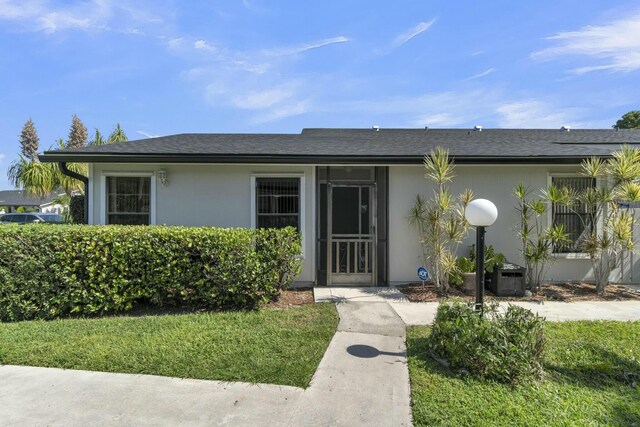 exterior space with stucco siding and a yard