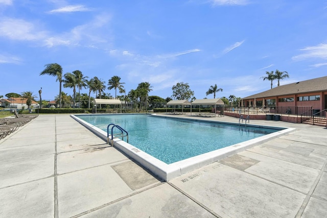community pool with a patio and fence