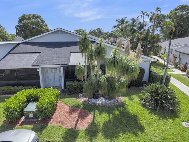 view of side of home featuring a shingled roof and a yard