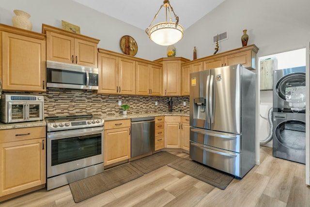 kitchen with tasteful backsplash, stacked washing maching and dryer, light wood finished floors, light brown cabinets, and stainless steel appliances