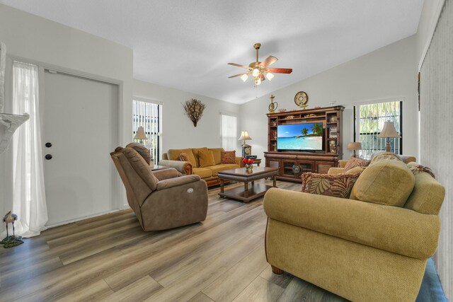 living area with a healthy amount of sunlight, a ceiling fan, wood finished floors, and lofted ceiling