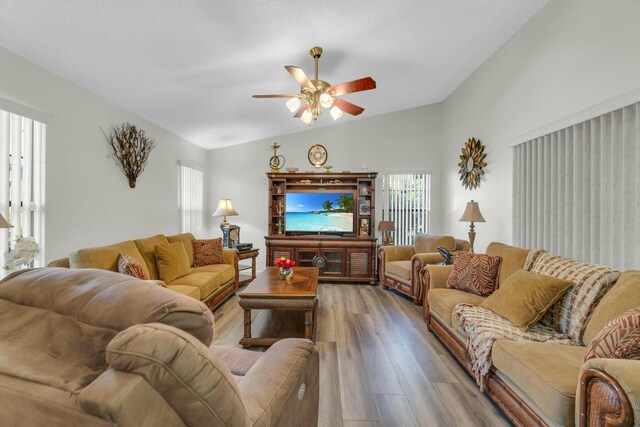 living area with high vaulted ceiling, ceiling fan with notable chandelier, light wood-type flooring, and visible vents