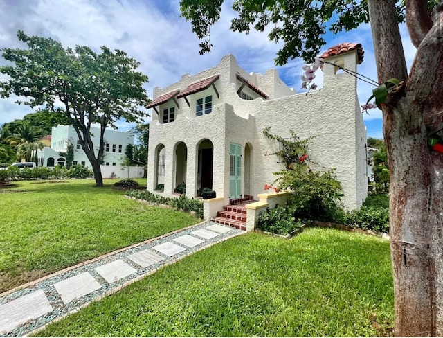 mediterranean / spanish-style house with a tiled roof, a front yard, and stucco siding