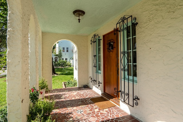 entrance to property featuring a porch and stucco siding
